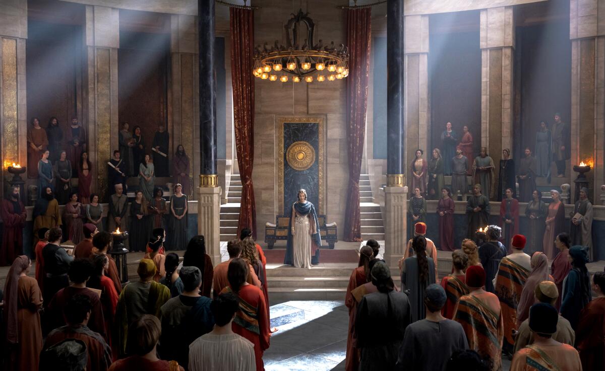 A queen stands in front of a gold seal in the middle of her court