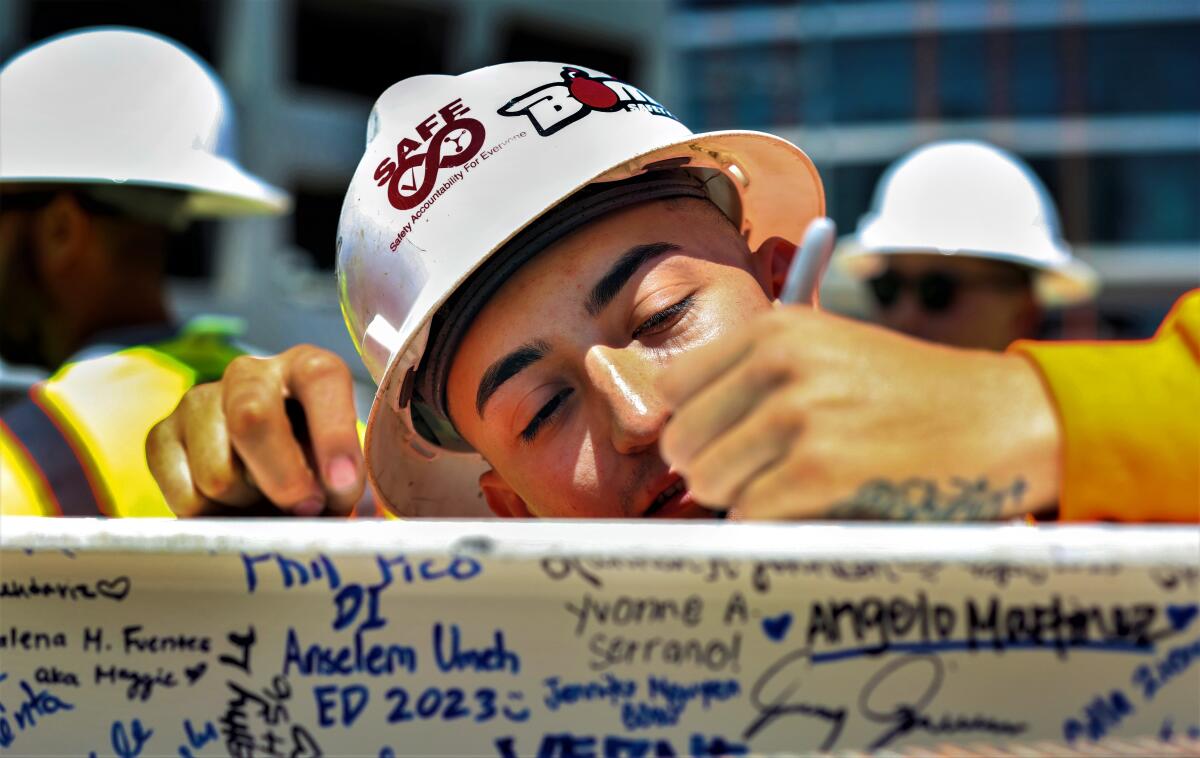 A construction crew worker Thursday signs a structural beam during a topping off ceremony held by UCI Health.