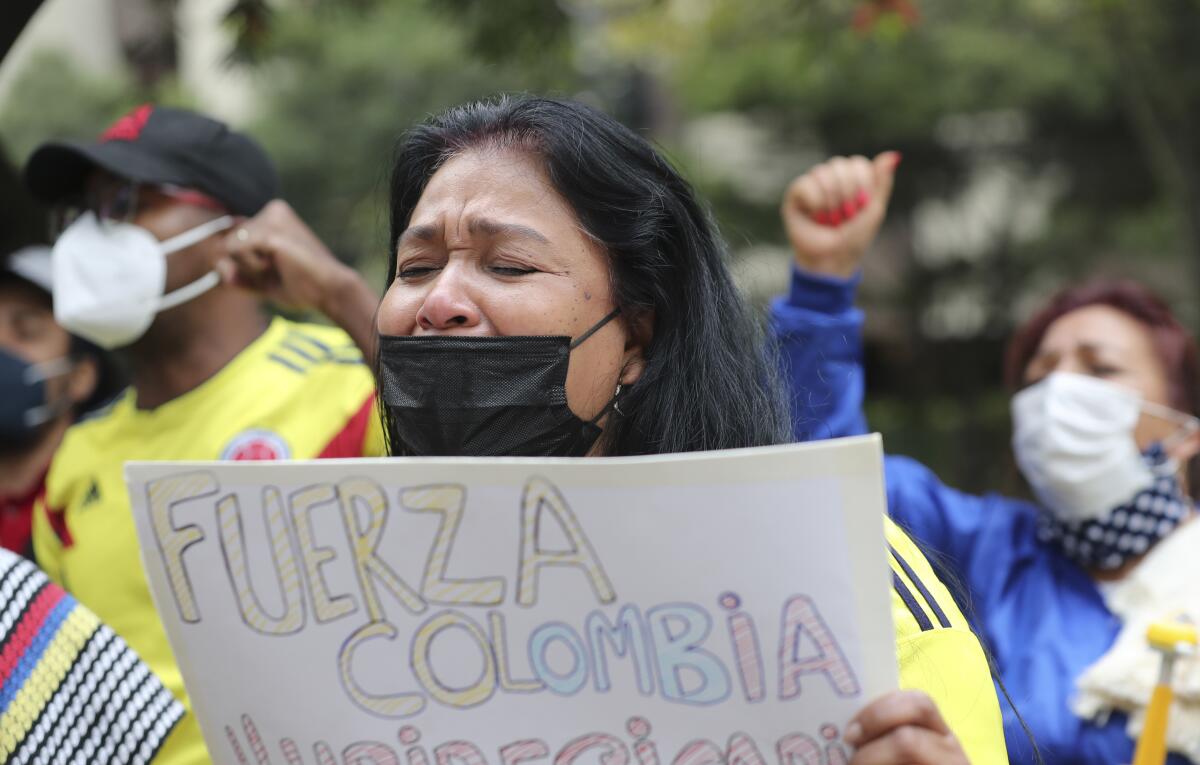 Una mujer llora mientras canta el himno nacional de Colombia 