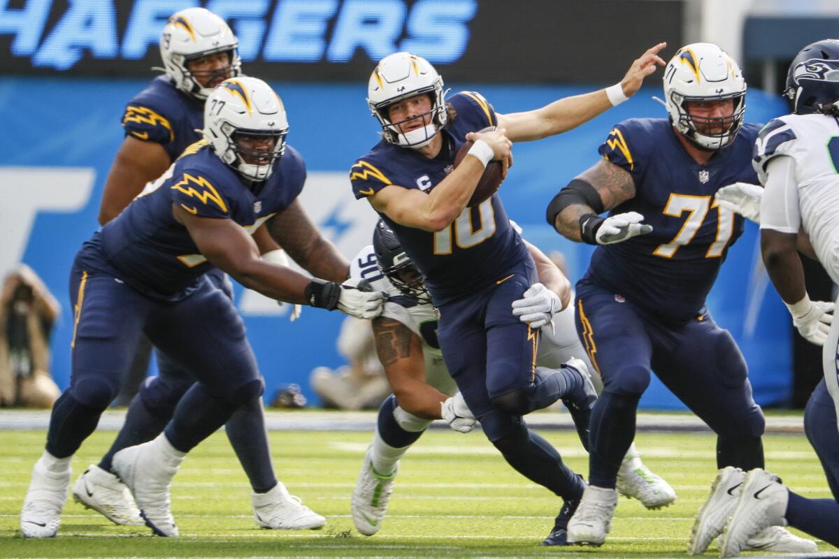 Chargers quarterback Justin Herbert struggles to avoid the grasp of Seattle Seahawks defensive tackle Bryan Mone.