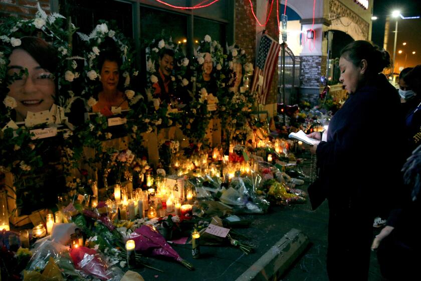 Martha Martinez, 51 of Monterey Park, recites the Rosary for the 11 shooting victims, at the memorial site in front of Star Ballroom Dance Studio in Monterey Park on Thursday, Jan. 26, 2023. Martinez has been coming daily to the memorial recite the Rosary.