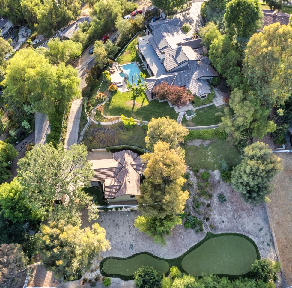 Aerial view of the estate with the house, pool, trees and grass.
