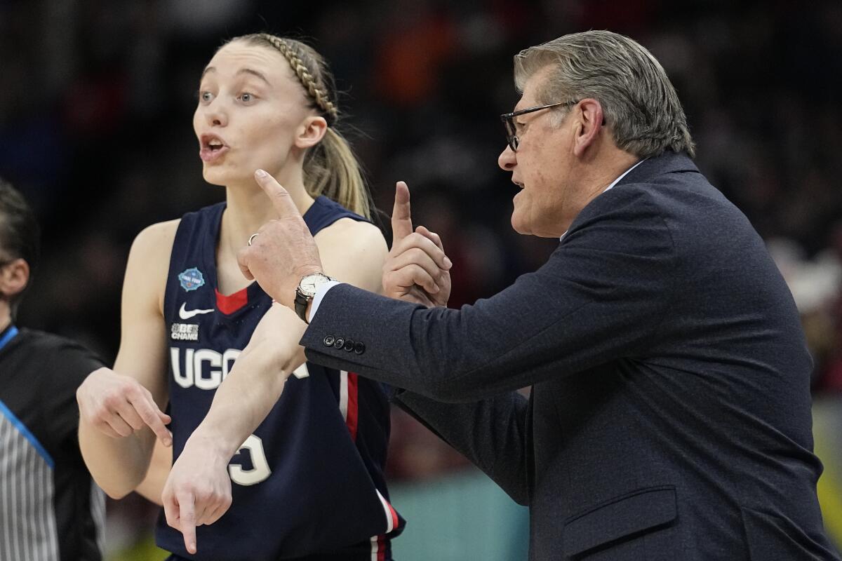 Connecticut coach Geno Auriemma and guard Paige Bueckers talk strategy April 1, 2022, in Minneapolis.