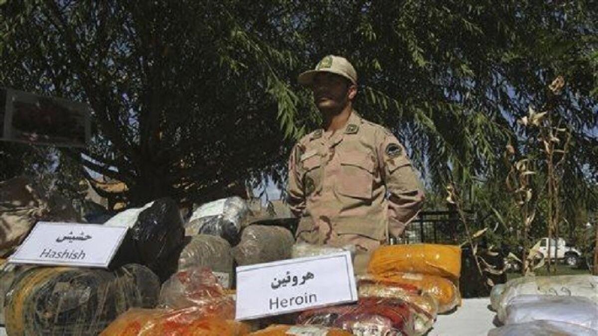 An Iranian police officer stands behind drugs seized from smugglers near the border with Afghanistan in 2014.