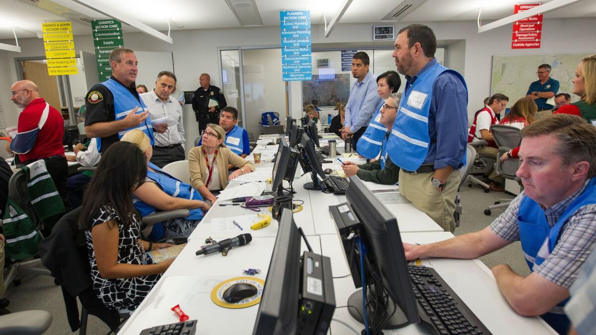 Mike Halphide, left, Newport Beach lifeguard battalion chief, speaks with city employees during an emergency response exercise at the city's Emergency Operations Center on Wednesday.
