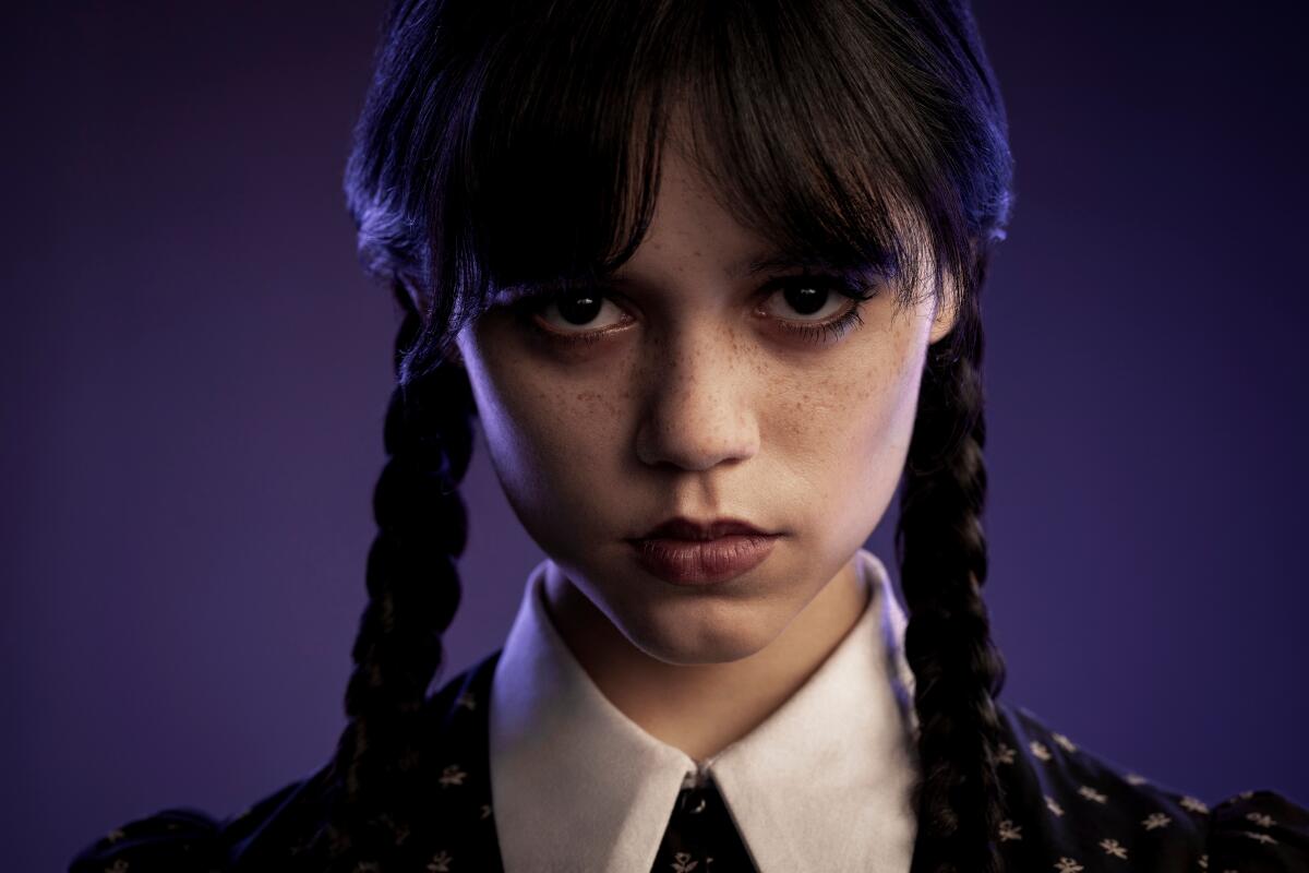 A girl with freckles and black braided pigtails wearing a collared dress