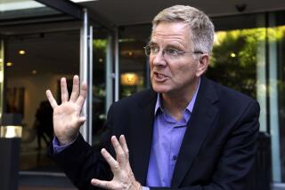 Rick Steves, wearing a blue shirt and dark blazer, speaks while motioning with his hands