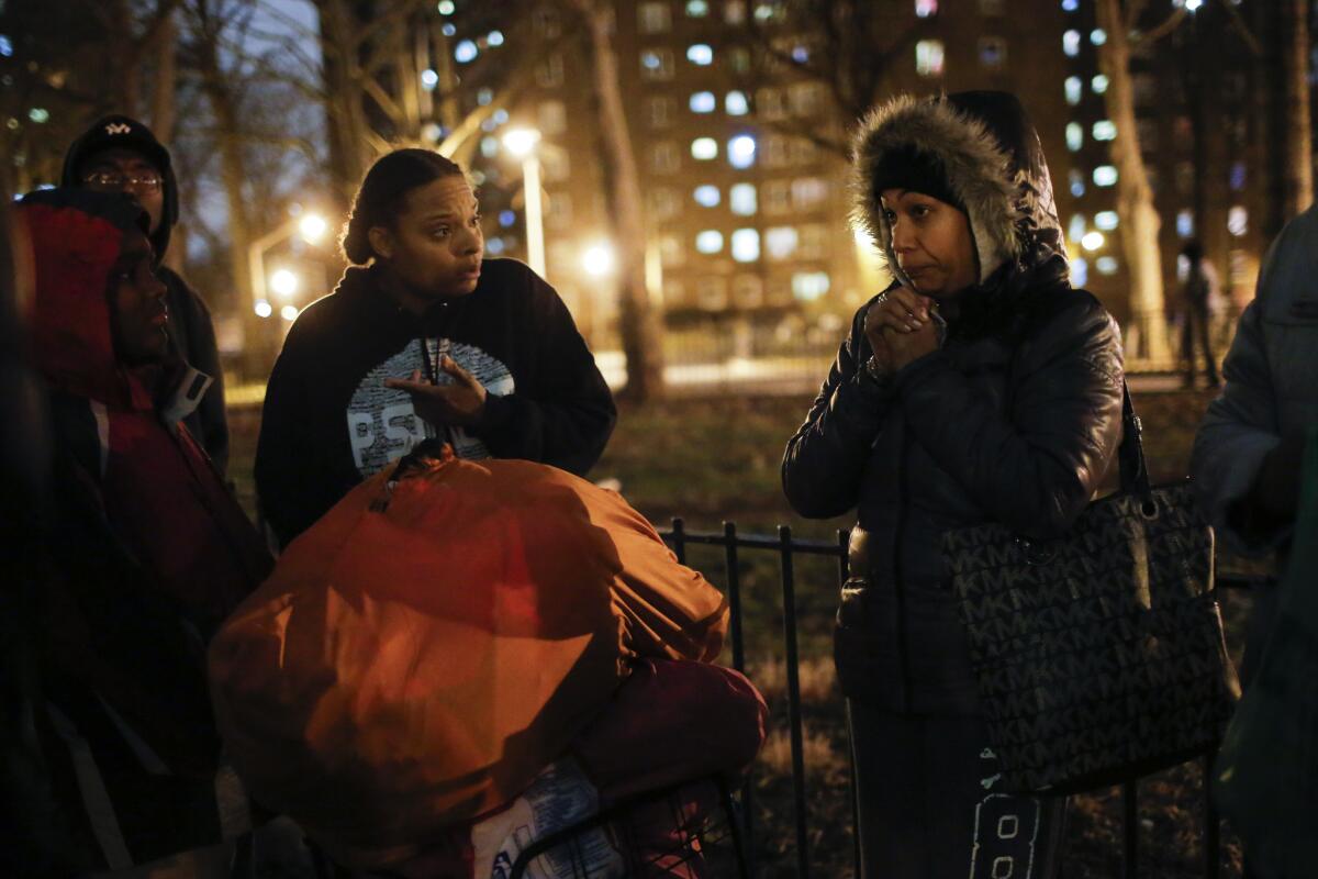 Residents stand near the Bronx, N.Y., housing complex where two police officers were shot and wounded.