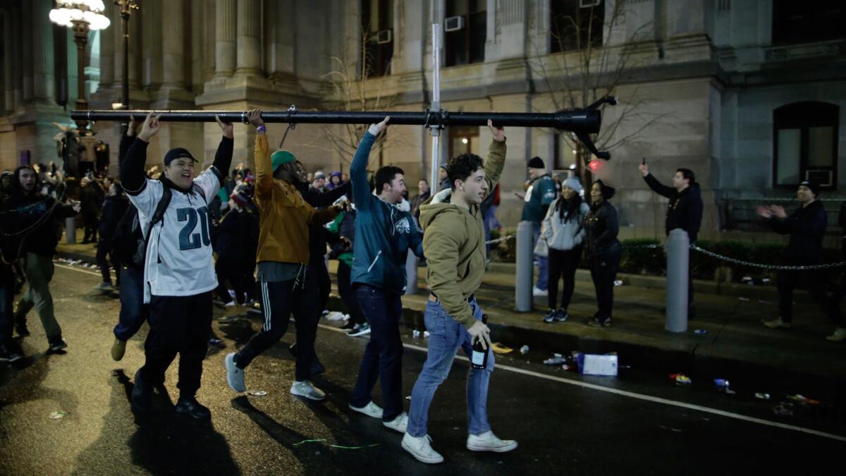 People carry a broken pole while celebrating the Eagles' victory in Super Bowl LII.