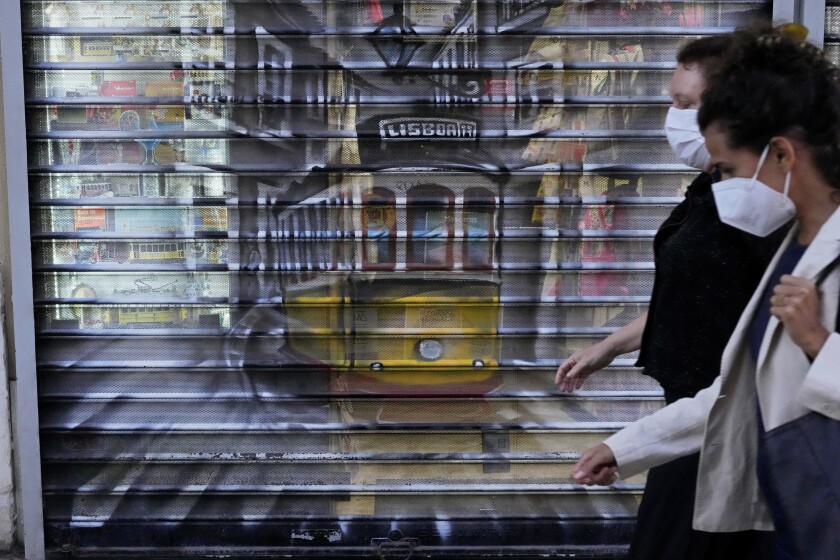 Two women walking past a shop decorated with a picture of a tram