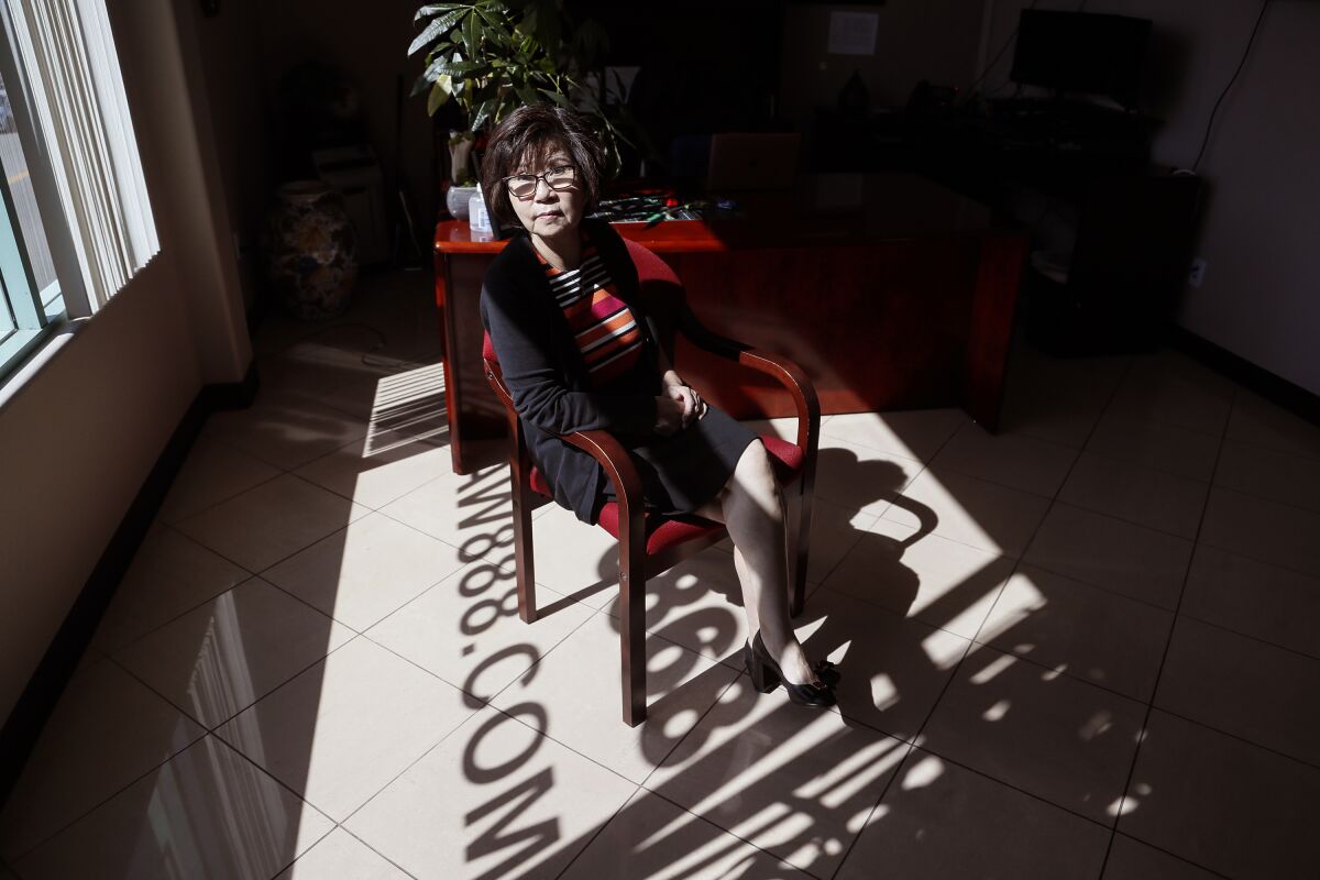 Tammy Wong poses for a portrait seated in a strip of sunlight in an office.
