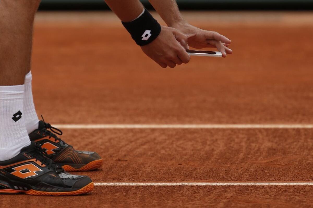 Sergiy Stakhovsky takes a picture of a ball mark with his cellphone.