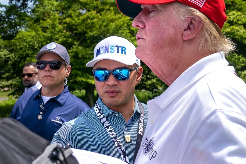 Walt Nauta, center, assists Former President Donald Trump as he greets supporters at the second round of the LIV Golf at Trump National Golf Club, Saturday, May 27, 2023, in Sterling, Va. (AP Photo/Alex Brandon)