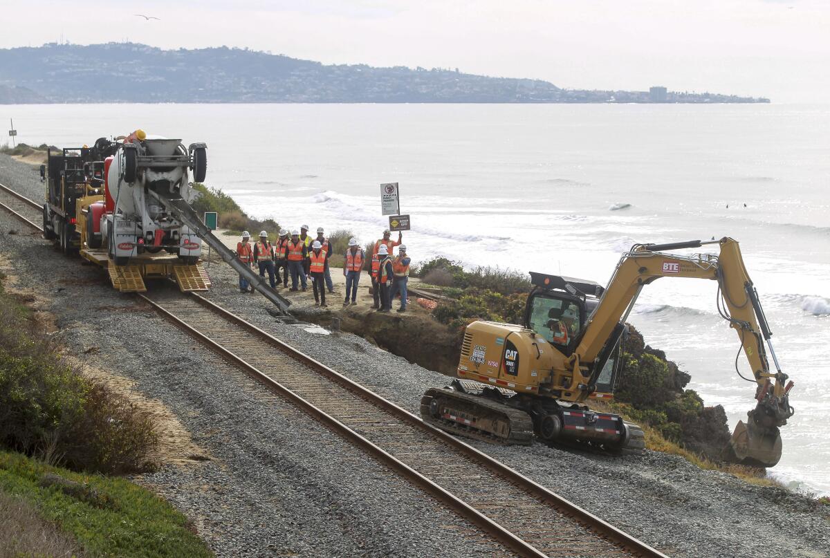 Workers repair the site of a bluff collapse next to the railroad tracks in Del Mar last year.