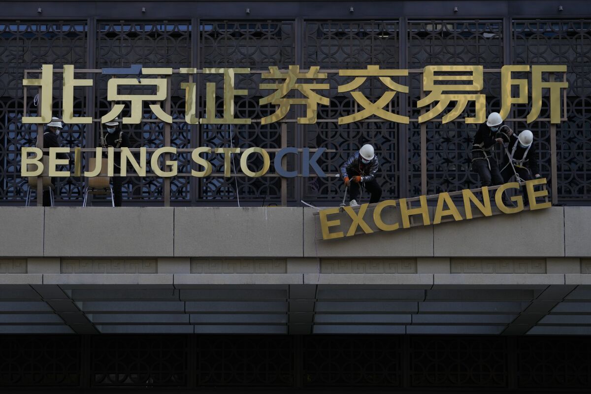 FILE - Workers install the nameplate of the Beijing Stock Exchange on the Financial Street in Beijing, Nov. 14, 2021. China on Thursday, Feb. 17, 2022, rejected a U.S. accusation that Beijing is failing to live up to its market-opening commitments in a new round of complaints as companies wait for the two governments to restart talks on ending a tariff war. (AP Photo/Andy Wong, File)