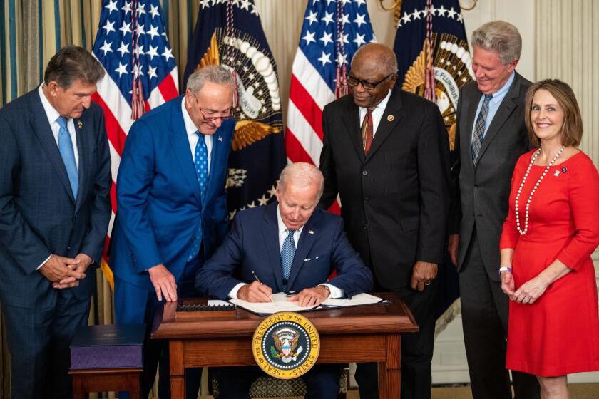 WASHINGTON, DC - AUGUST 16: President Joe Biden, center, flanked by (L to R) Sen. Joe Manchin (D-WV), Senate Majority Leader Chuck Schumer (D-NY), House Majority Whip Jim Clyburn (D-SC), Rep. Frank Pallone (D-NJ), and Rep. Kathy Castor (D-FL) delivers remarks and signs H.R. 5376, the Inflation Reduction Act of 2022 into law in the State Dining Room of the White House on Tuesday, Aug. 16, 2022 in Washington, DC. The 737 billion dollar bill focuses on climate change, lowering health care costs and creating clean energy jobs. (Kent Nishimura / Los Angeles Times)