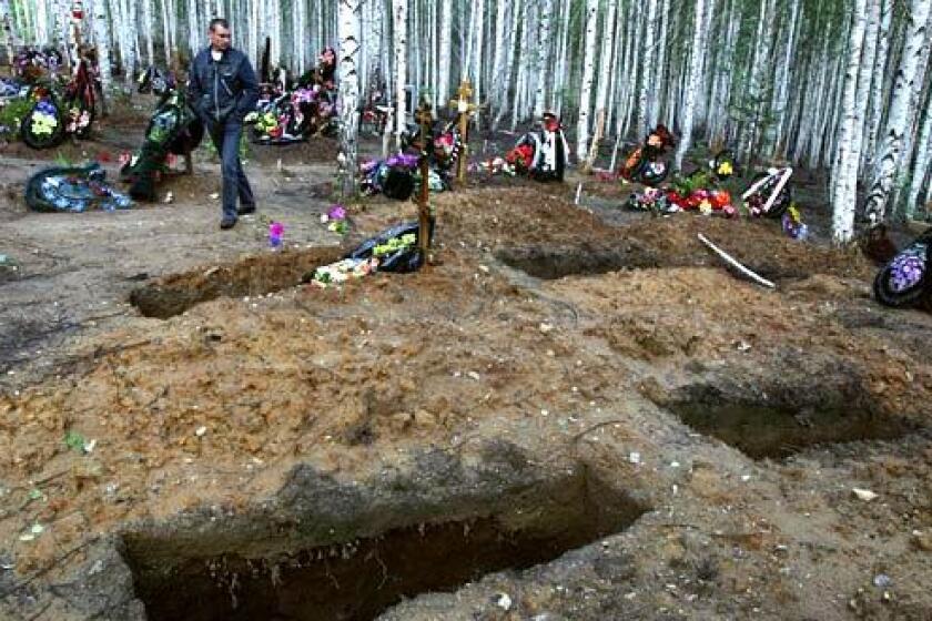 FRESHLY DUG: Andrei Yudin passes some freshly dug graves as he walks across Karabash cemetery.