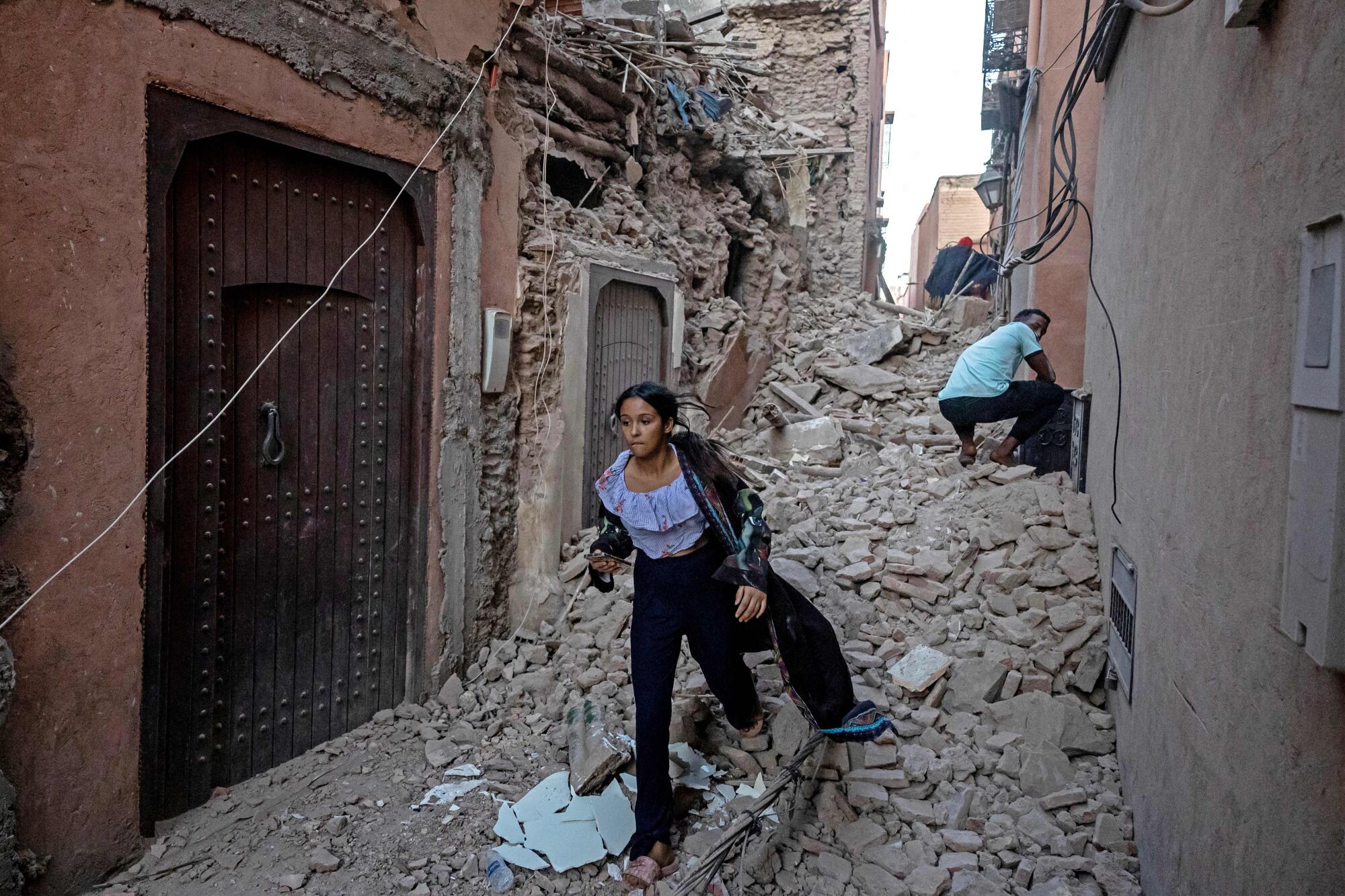 A woman evacuates with her belongings through the rubble in the earthquake