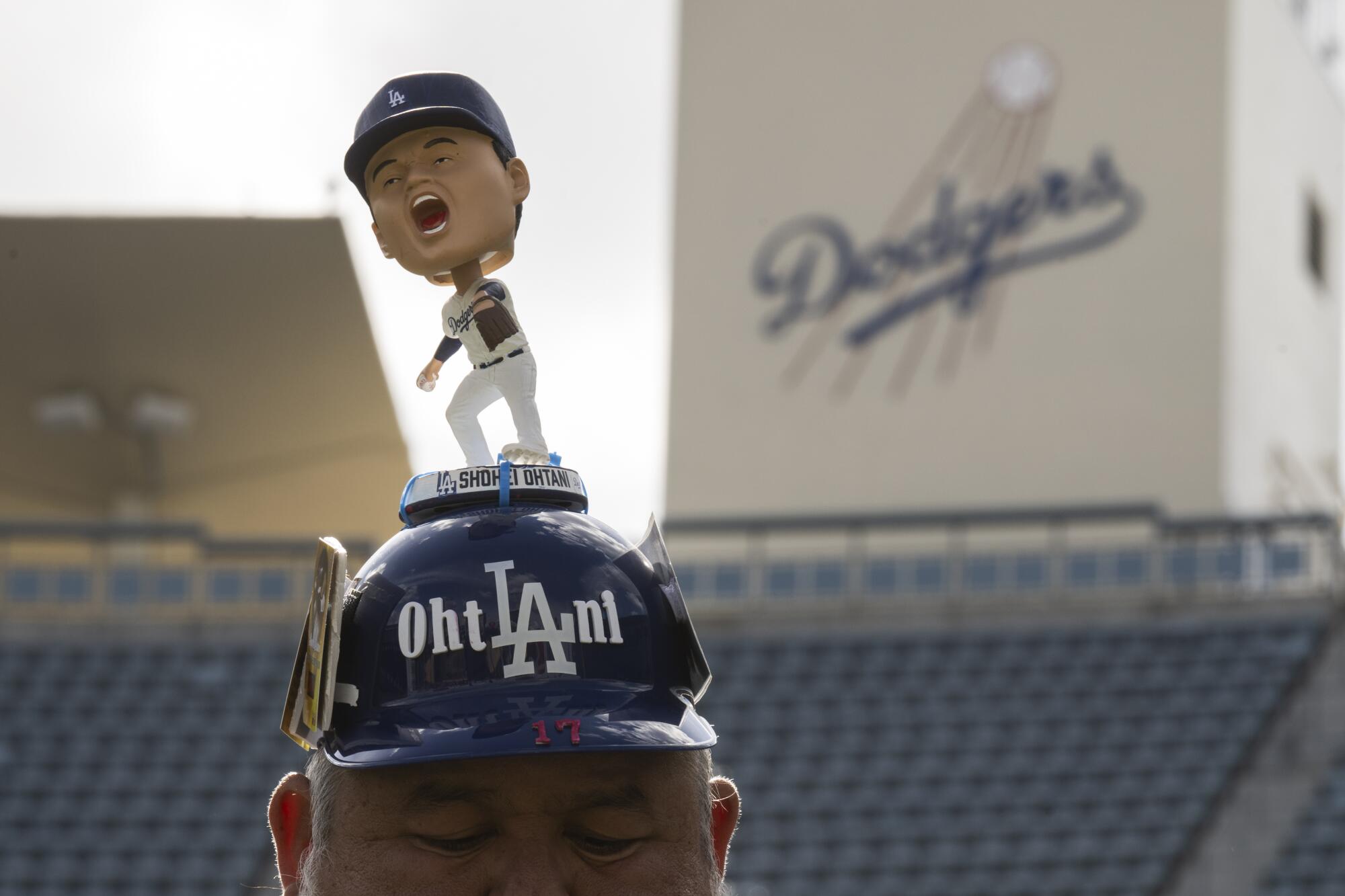 道奇队球迷阿尔贝托·巴伦苏埃拉 (Alberto Valenzuela) 戴着带有 Shohei Ohtani 摇头公仔的击球头盔，出席在道奇体育场举行的道奇节 (DodgerFest)。