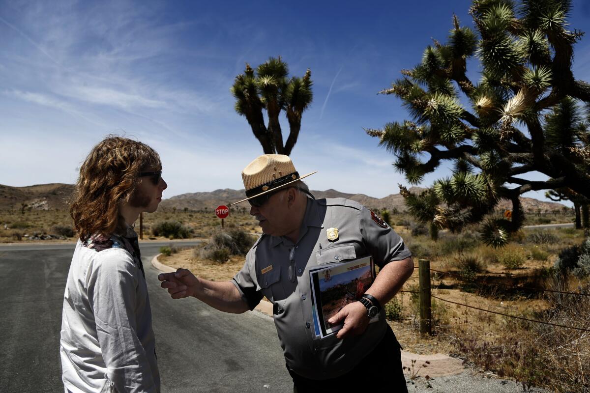 Charlie Salvidge, 29, of London, listens to park ranger George Land tell the story of where musician Gram Parsons’ body was burned in 1973. More photos