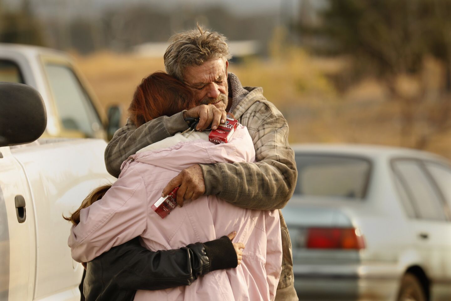 David Neeley hugs his ex-wife, Jeanne Neely, and their daughter, Faith Neeley, 10, in a parking lot in Oroville, where they are staying amid the Camp fire.
