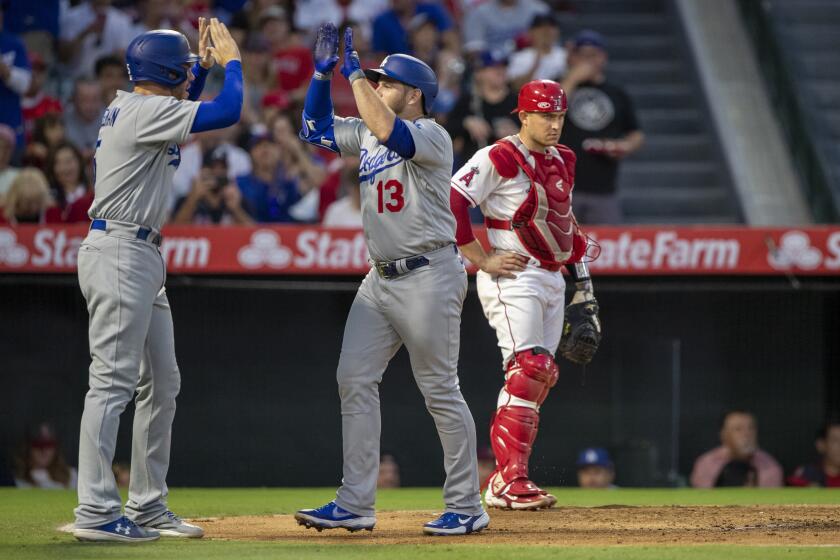 Dodgers' Max Muncy, center, is congratulated bt Freddie Freeman for homering against the Angels on July 16, 2022, in Anaheim.