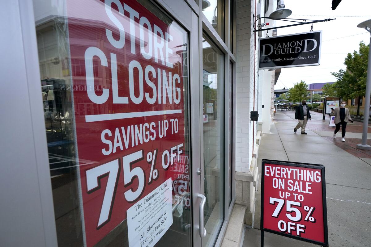 Passersby walk past a business storefront