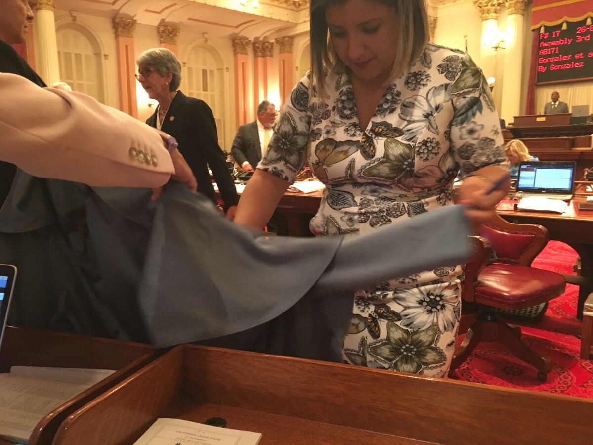 Sen. Melissa Hurtado (D-Sanger) inspects a jacket she was wearing just after it was splashed with a red liquid from a protester in the balcony of the Senate chambers.