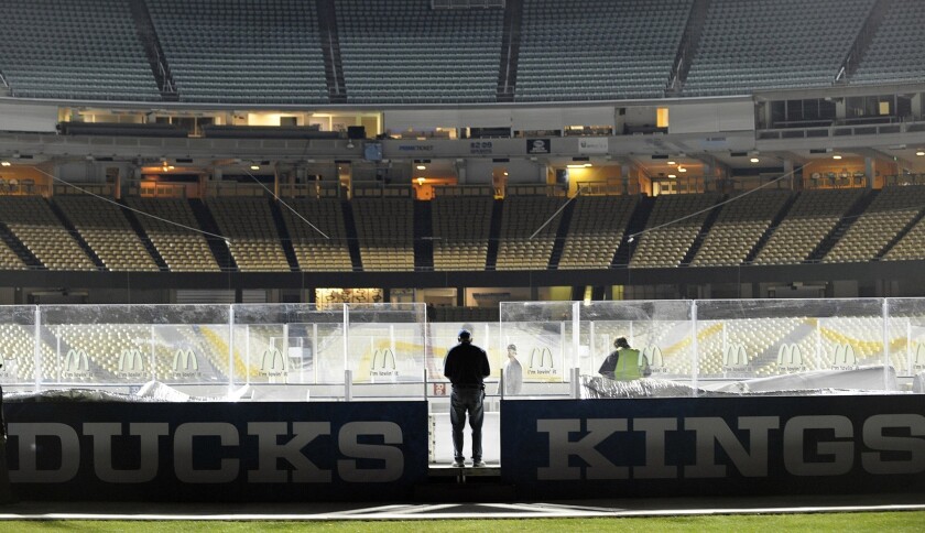 Dan Craig, senior director of facilities operations for the NHL, keeps an eye on proceedings as workers maintain the ice that will be used for Saturday's game between the Ducks and Kings at Dodger Stadium.