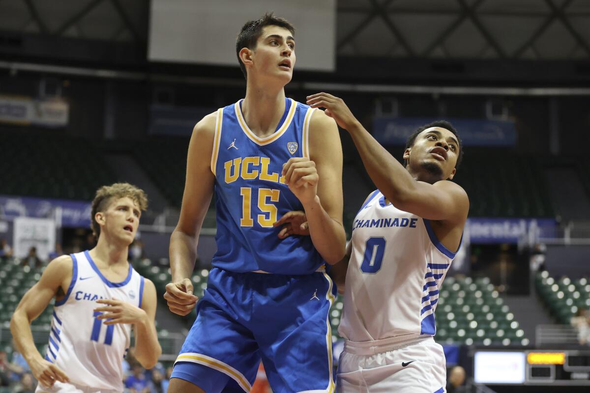 UCLA 7-foot-3 center Aday Mara towers over Chaminade opponents as he posts up in near the basket.