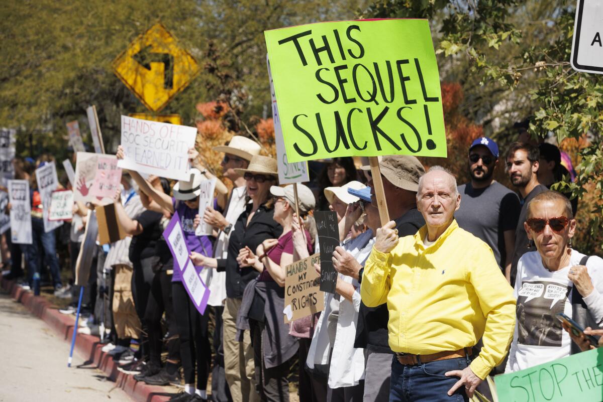 An anti-Trump demonstration in which people carry signs. One says This sequel sucks.