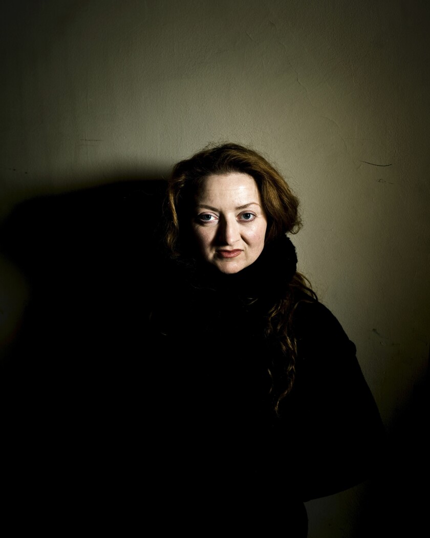 A woman wearing black against a gray wall.