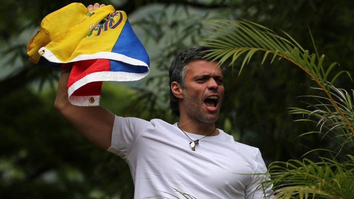 Opposition leader Leopoldo Lopez holds a Venezuelan national flag as he greets supporters outside his home in Caracas on Saturday.