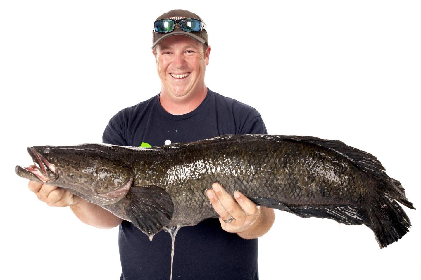 Caleb Newton poses with the 17-pound, 6-ounce northern snakehead fish he caught in Aquia Creek this summer.