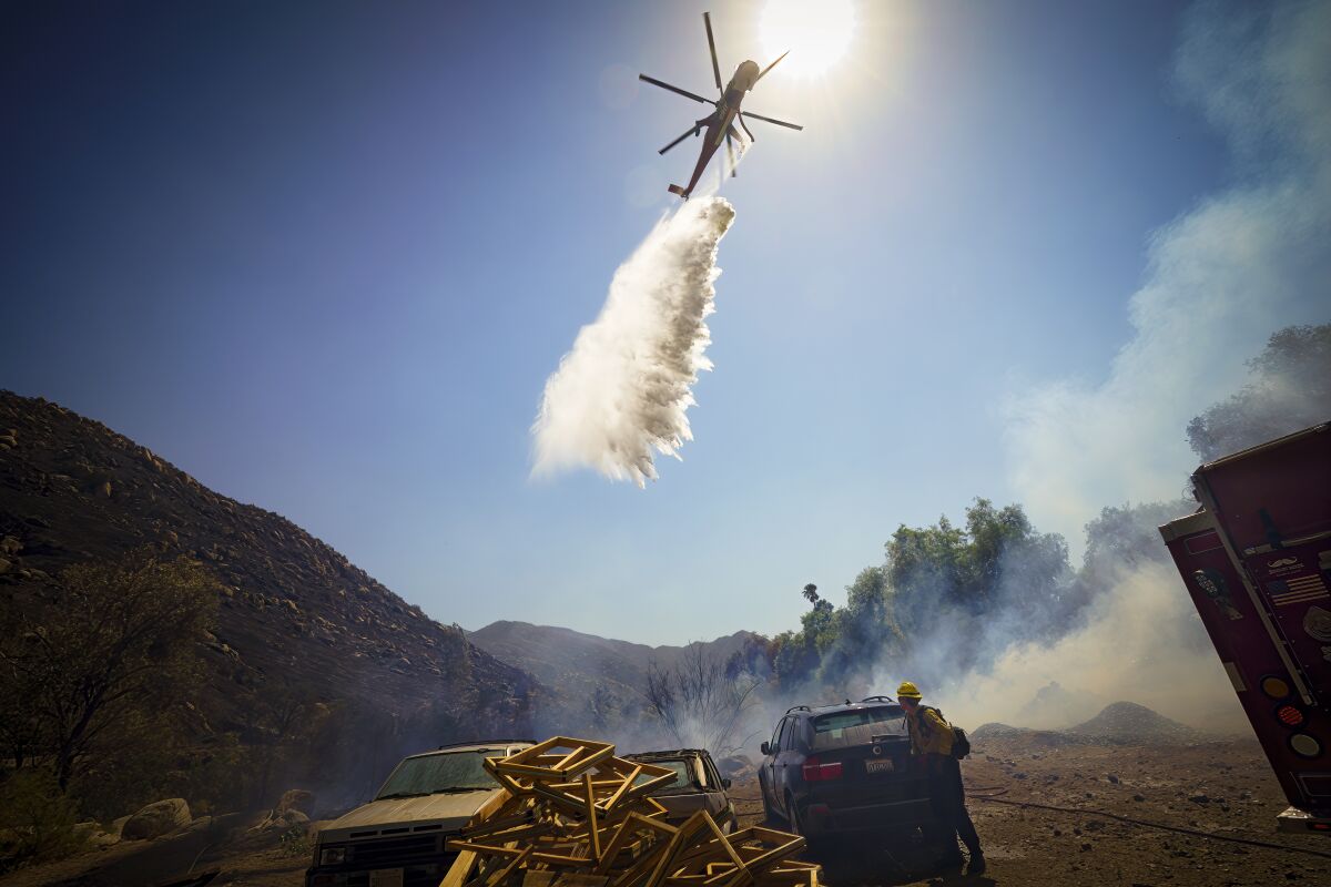 A firefighting helicopter drops water onto a brush fire that threatend homes near Barrett Lake Mobile Home Park.