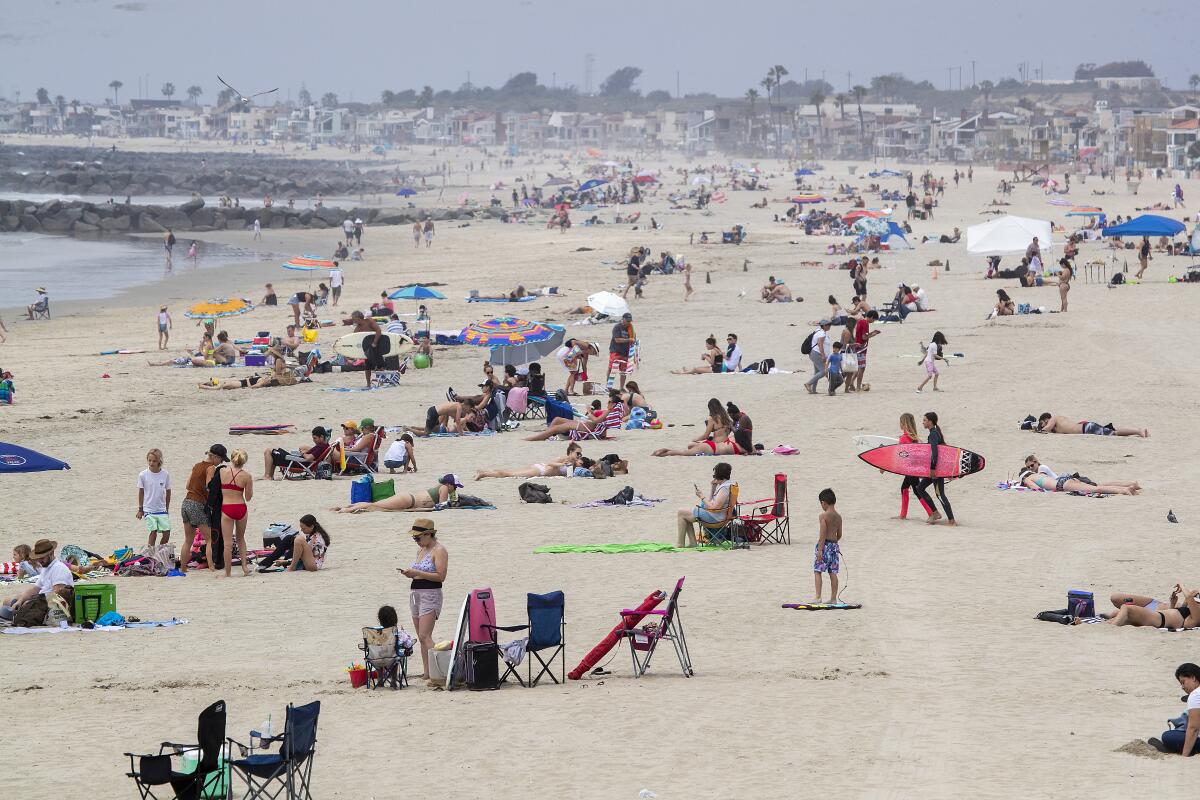 Beachgoers enjoy a day on the beach near the pier in Newport Beach, on Tuesday.