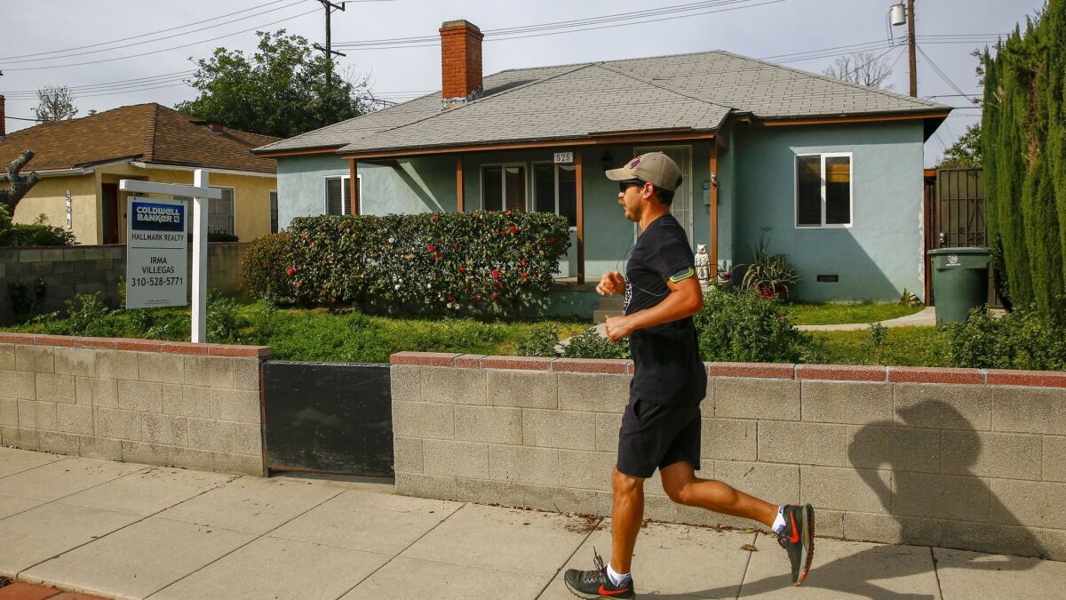 A runner runs jogs past a home for sale on Buena Vista Street in Burbank in March.