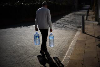 Joan Torrent, de 64 años, camina hacia su casa con jarrones de agua llenados en una fuente natural en Gualba, a unos 50 kilómetros (31 millas) al oeste de Barcelona, España, el 31 de enero de 2024. (Foto AP/Emilio Morenatti)