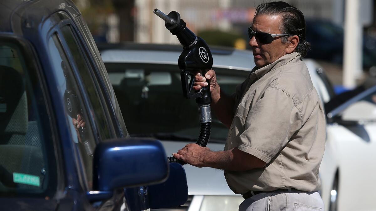 A customer prepares to pump gasoline into his car at an Arco gas station in Mill Valley, Calif. State lawmakers are considering a new tax on oil pumped from the ground, which could affect gas prices.