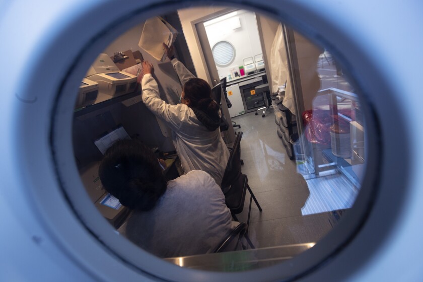 Lab workers seen through a small circular window