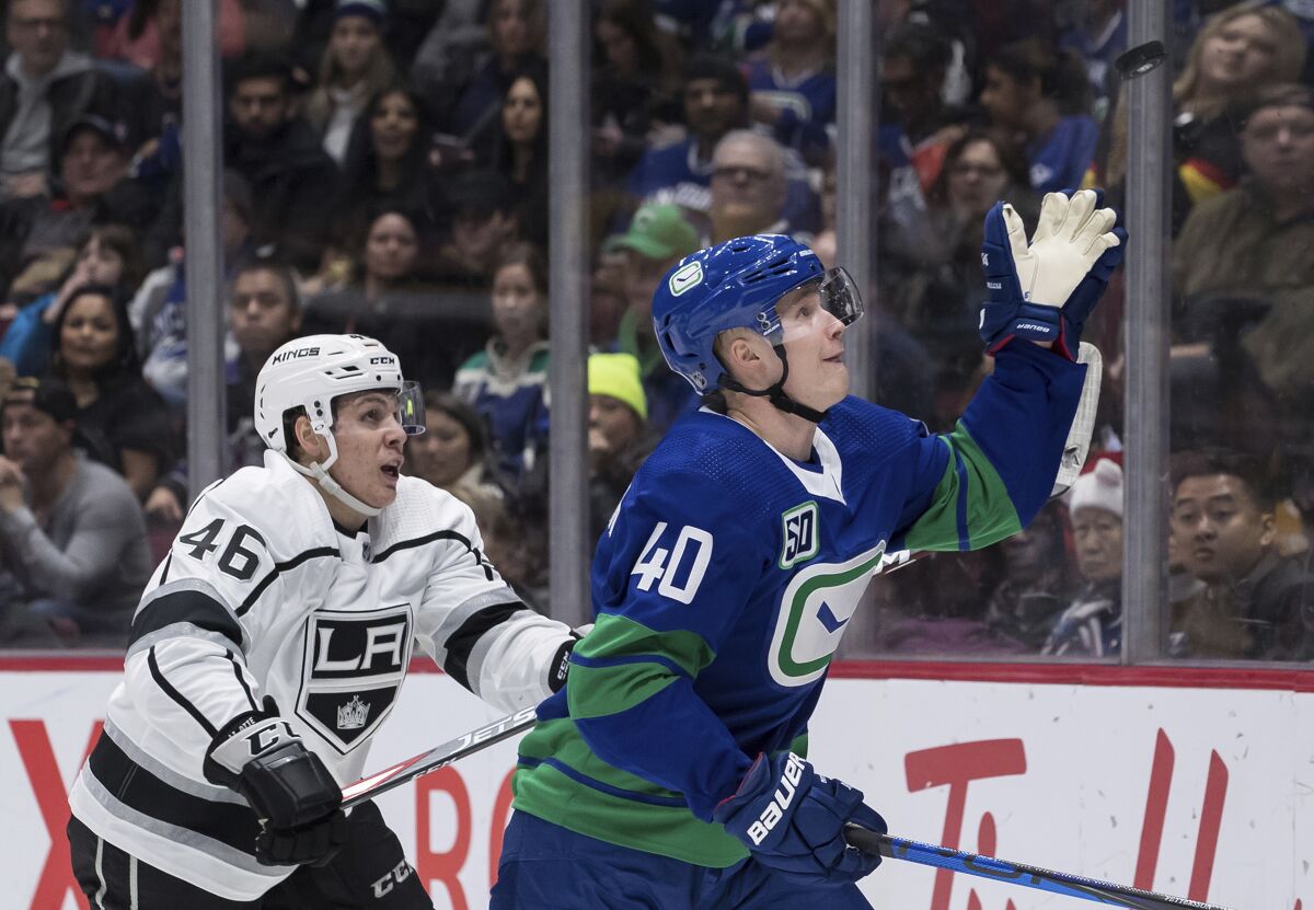 The Canucks' Elias Pettersson, right, reaches for the puck in front of the Kings' Blake Lizotte during the third period Saturday.
