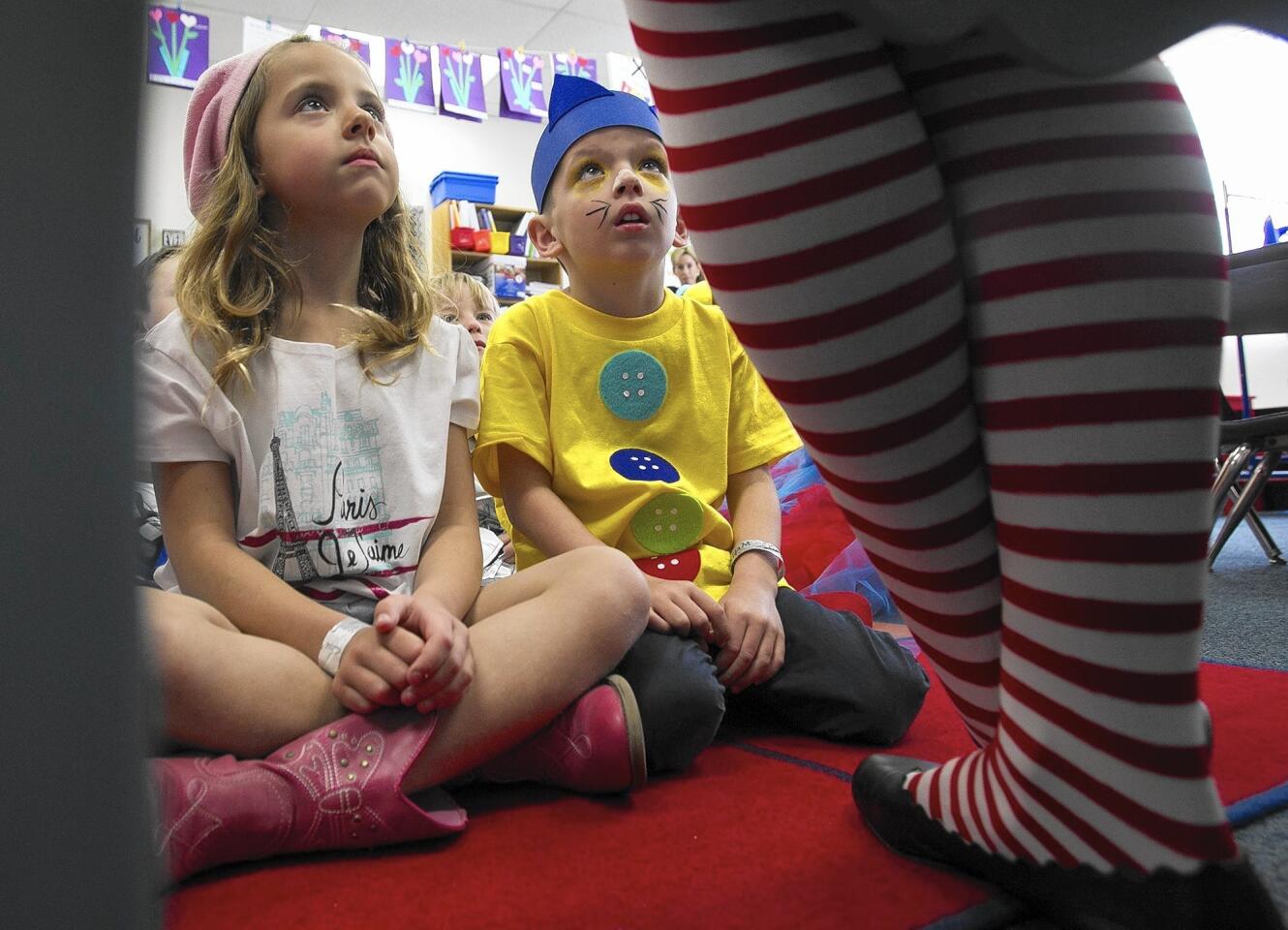 Charlotte Evatt, dressed as Grace from "American Girls" and Jackson Hammans dressed as Pete the Cat, listen to Megan Shahabi, the vice principal of Mariners Christian School in Costa Mesa, read in during a celebration of National Reading Day on Tuesday.