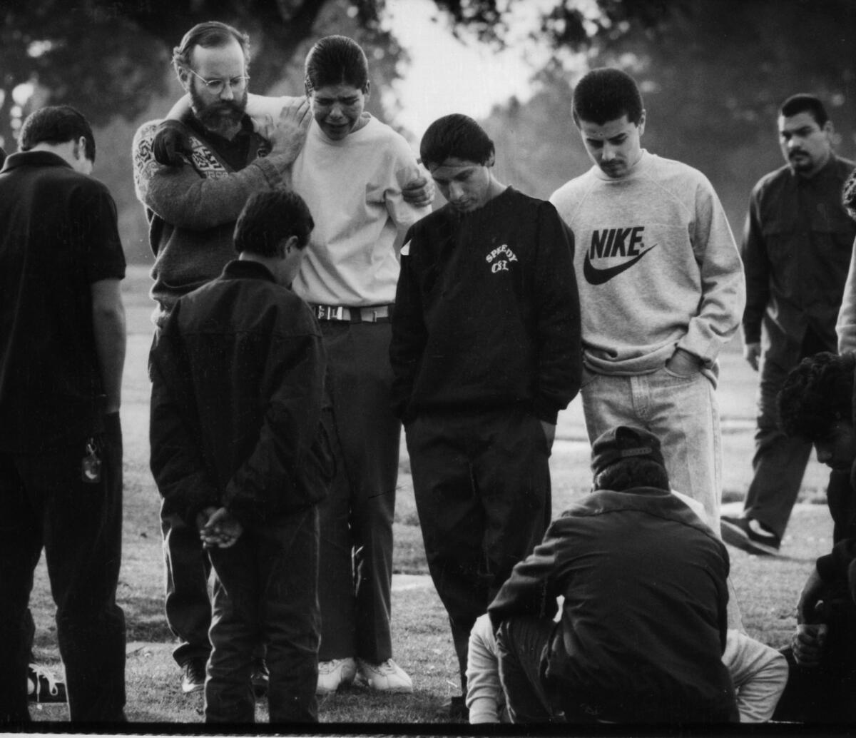 Father Gregory Boyle consoles gang members in February 1990 as they visit a grave. Boyle recently buried his 231st young person killed as a result of gang violence.