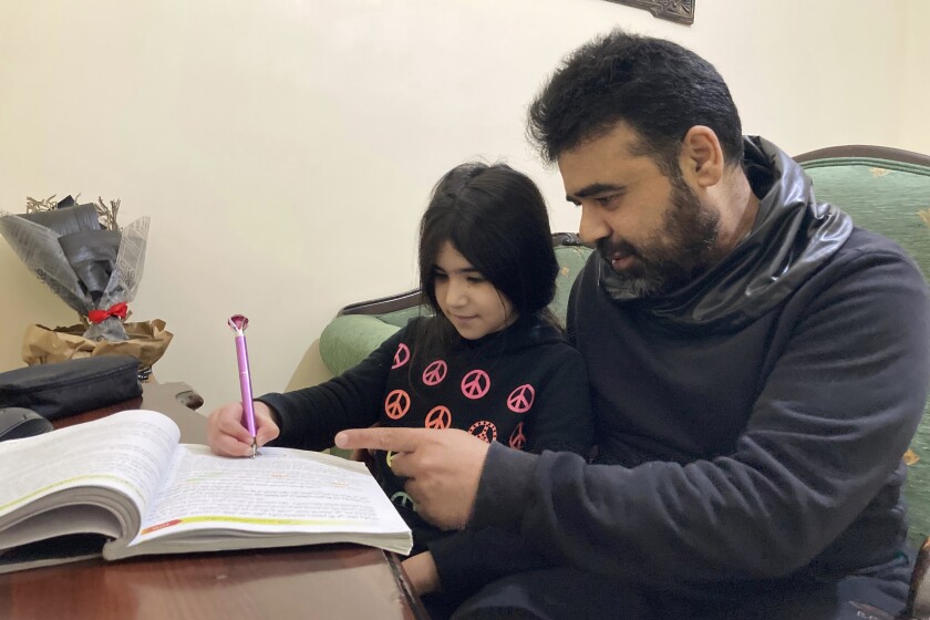 Syrian refugee Mahmoud Mansour, 47, helps his youngest daughter Sahar, 8, with her homework at his rented apartment in Amman, Jordan, Wednesday, Jan. 20, 2021. President Joe Biden has vowed to restore America's place as a world leader in offering sanctuary to the oppressed by raising the cap on the number of refugees allowed in each year. Mansour's family had completed the work to go to the United States when the Trump administration issued its travel ban barring people from Syria indefinitely and suspending the refugee program for 120 days. (AP Photo/Omar Akour)