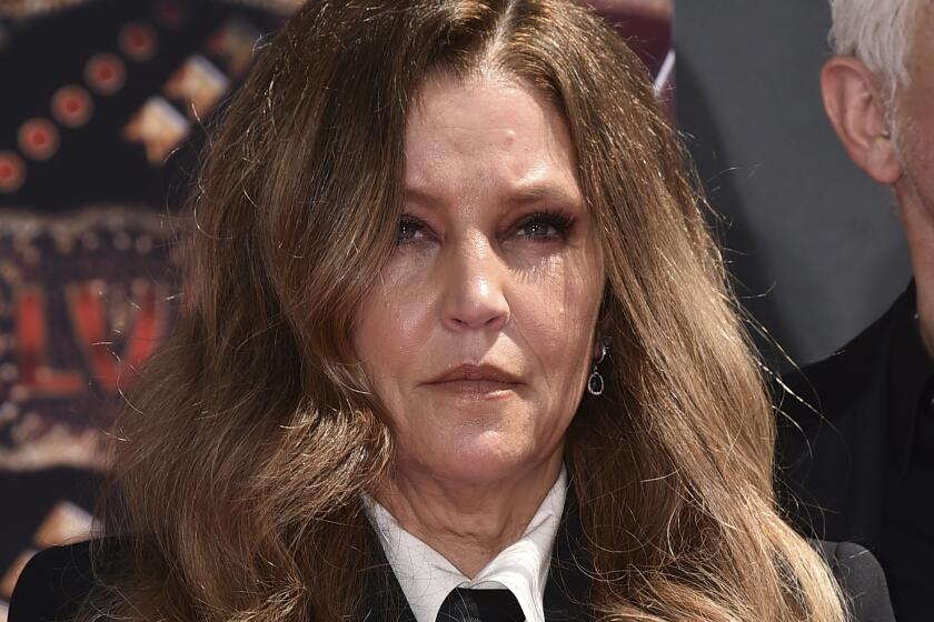 A woman with long brown hair stares forward at an event