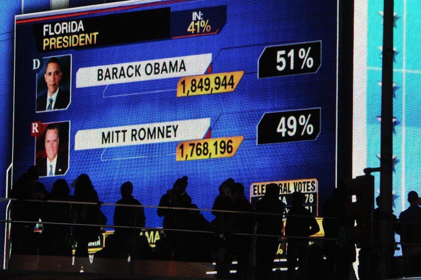 People watch large screens in Times Square as results in the 2012 presidential election are broadcast.