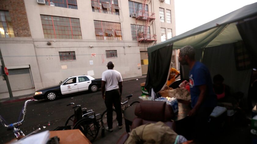 Police patrol Skid Row as homeless residents look on in Los Angeles on September 28, 2017.