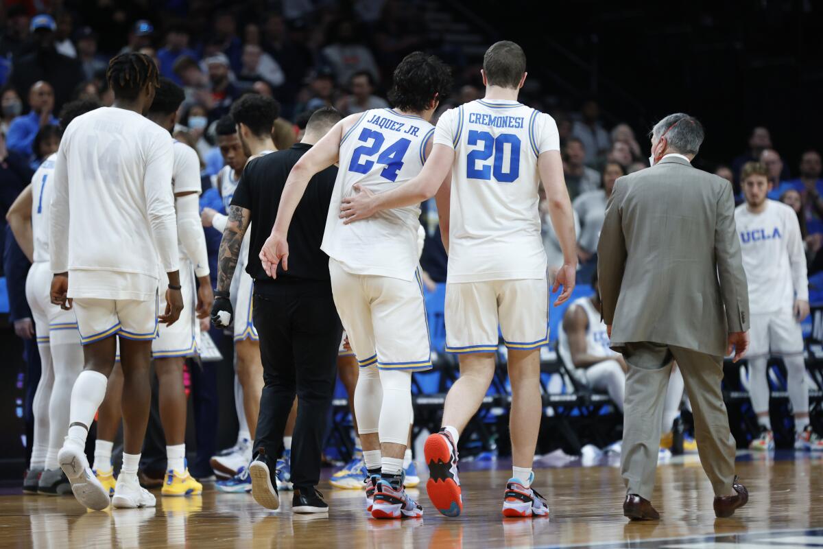 UCLA's Jaime Jaquez Jr. (24) is helped off the court by Logan Cremonesi (20) after Jaquez was injured March 19, 2022.