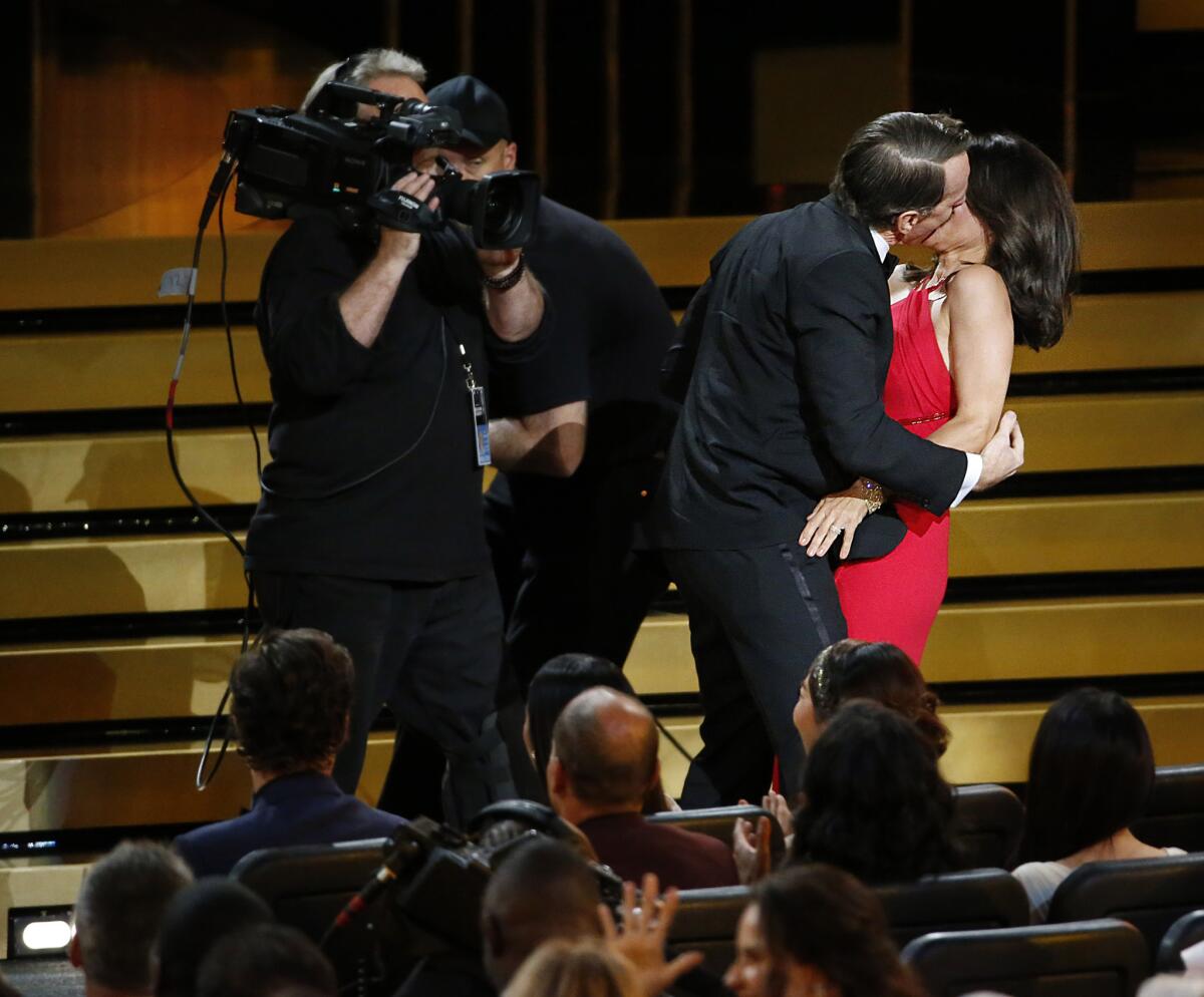 Actress Julia Louis-Dreyfus is kissed by actor Bryan Cranston during the Emmy Awards at Nokia Theatre L.A. LIVE.