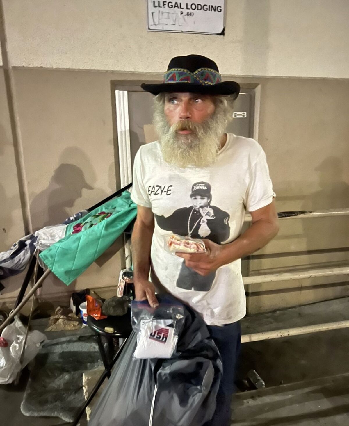 Jeffrey Gickow, from Michigan, who used to drive a pedi-cab here, camps out under an illegal lodging sign in East Village.